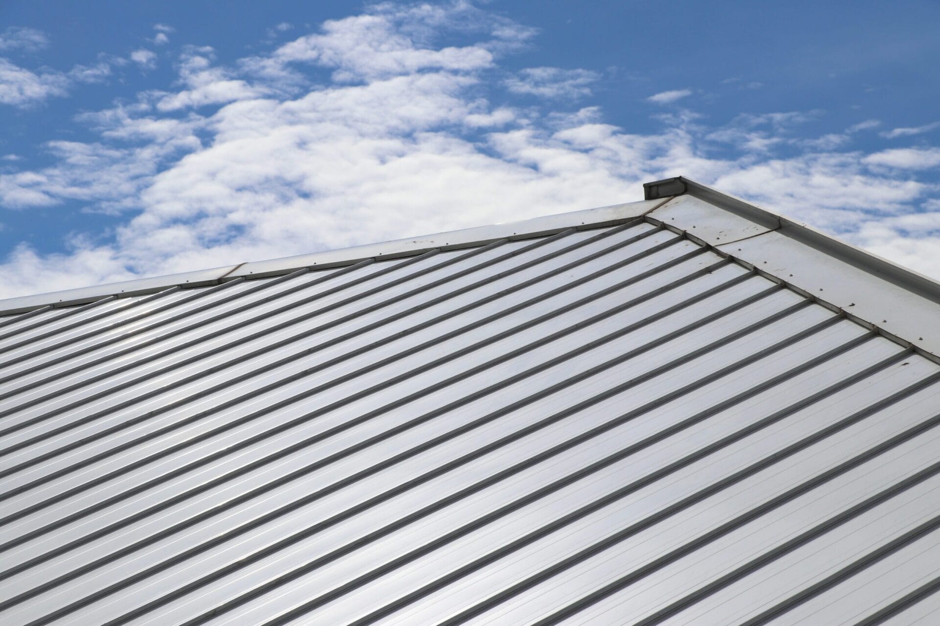 Metal,Sheet,Roof,And,Slope,With,Clouds,And,Blue,Sky shutterstock 1414776107 scaled